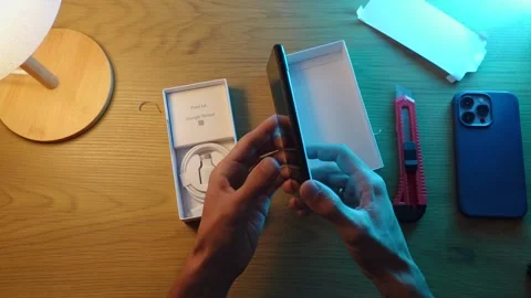 Technoblogger unpacks a box with a new google piel 6a phone Stock Footage 252770649