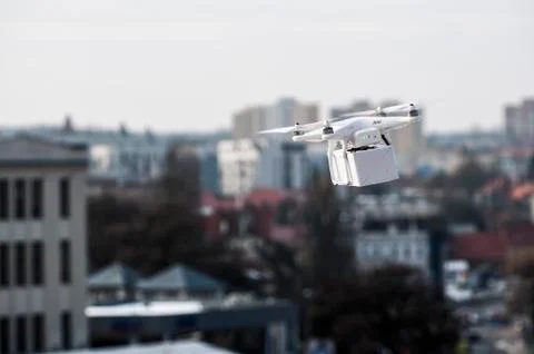 Technological delivery innovation - fast drone delivery concept above town Stock Photos
