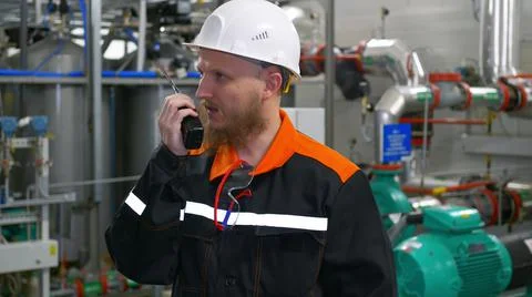 Technological engineer in a white helmet transmits instructions to the staff Stock Photos