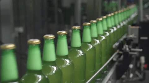 Technological line for bottling beer. Green bottles filled with beer move along Vidéo 151888555