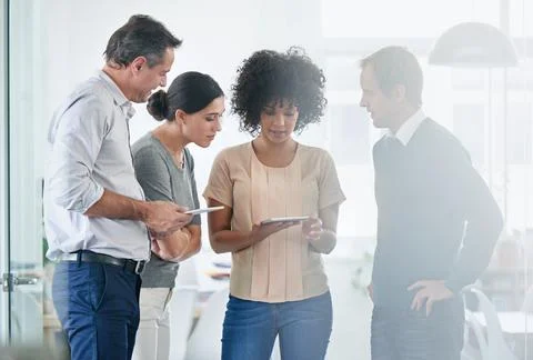 Technological teamwork. Shot of a group of colleagues using a digital tablet Stock Photos