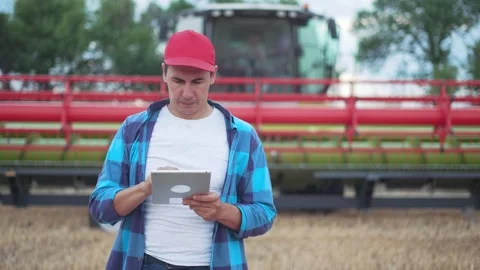 Technologies in agriculture. man with tablet on background of tractor machine Stock-Footage 252108823