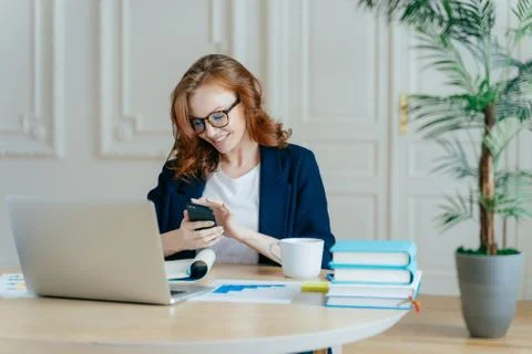 Technology and communication concept. Red haired young female checks email bo Foto stock