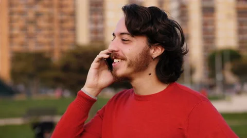 Technology, communication - smiling young man talks on his smartphone - outdoor Stock Footage 142967077