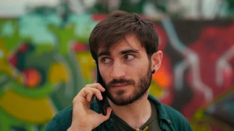 Technology, communication - young man talks on phone looking around cautiously Stock Footage 151537254