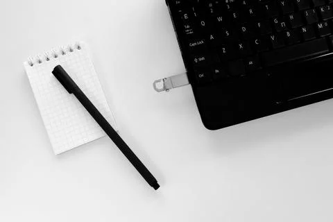Technology concept of notepad and pen, laptop and flash drive Stock Photos