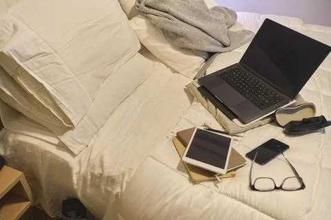 Technology devices on bed creating a study area Фото