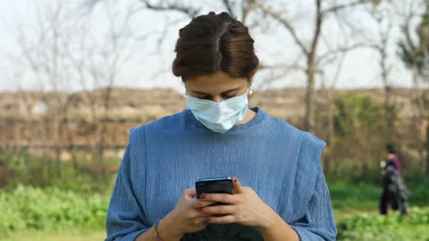 Technology - girl with mask smiles while writing a message on social  Stock-Footage 143078166
