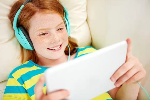 Technology makes for easy after school entertainment. a little girl using a Stock Photos
