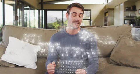 Technology presenter on beige couch explaining data flow while binary code Stock Footage 318688928