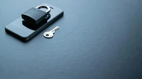 Technology security. Modern space grey mobile phone with padlock, key on dark Stock Photos
