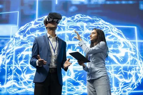 Technology specialist using VR goggles next to woman looking at virtual AI Stock Photos
