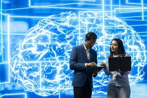 Technology startup colleagues comparing AI model code on laptop and tablet Stock Photos
