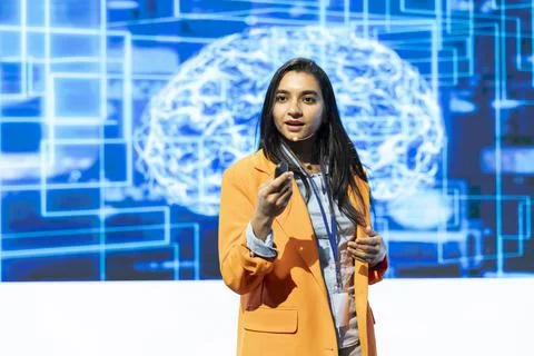 Technology summit presenter speaking in front of AI digital brain visualization Stock Photos