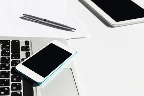 Technology workspace featuring laptop, tablet, and smartphone during daytime Stock Photos