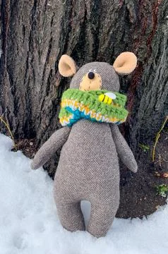 Teddy bear with colorful knitted scarf sitting on the snow Stock Photos