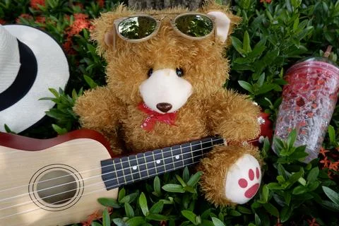 Teddy bear with glasses under the tree playing guitar Foto stock