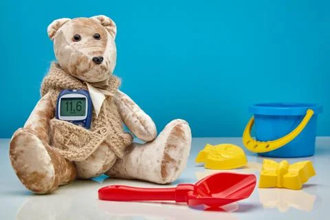 Teddy bear with a glucometer and scattered children's toys Stock Photos