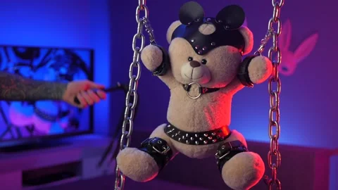 Teddy bear in leather harnesses BDSM accessory hand in the neon light Stock Footage 150354487