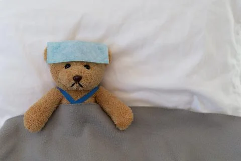 Teddy bear lying sick in bed. Teddy bear with antipyretic patch Foto stock