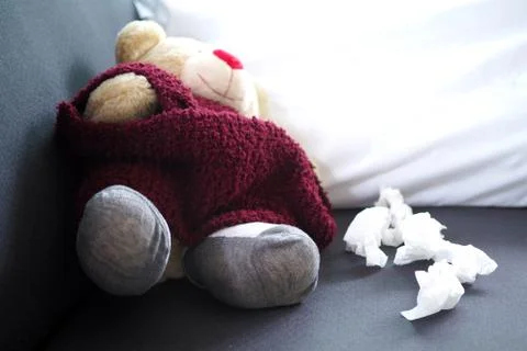 Teddy bear lying sick on the sofa inside the house. The concept of sick child Stock Photos
