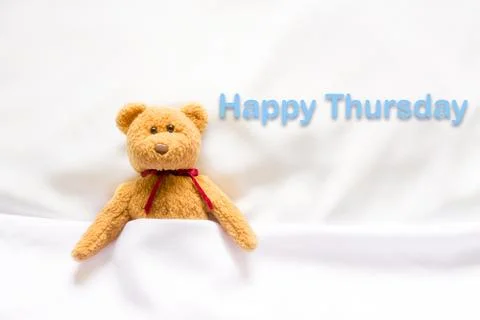 Teddy Bear lying in the white bed with message " Happy Thursday"  Stock Photos