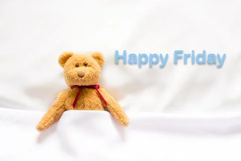 Teddy Bear lying in the white bed with message " Happy Friday"  Stock Photos