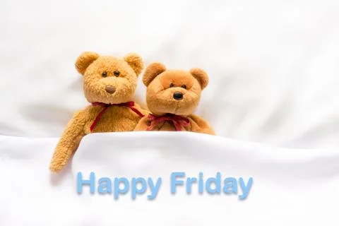 Teddy Bear lying in the white bed with message " Happy Friday"  Stock Photos