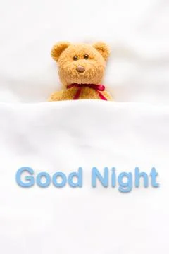 Teddy Bear lying in the white bed with message "Good night " Stock Photos