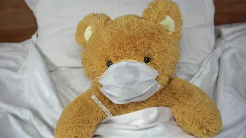 A teddy bear measures the temperature with a mercury thermometer. The bear lies Stock Footage 131009184