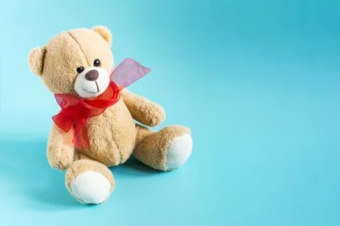 A teddy bear with a red bow on a light background. Stock Photos