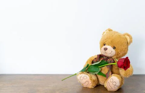 Teddy bear with a red rose on a wooden surface with white background Stock Photos