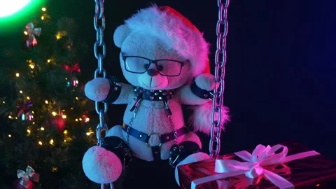 A teddy bear in a Santa Claus hat is a Christmas gift for BDSM games on chains Stock Footage 165225519