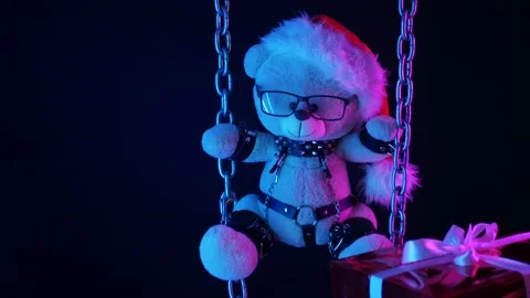 A teddy bear in a Santa Claus hat is a Christmas gift for BDSM games on chains Stock Footage 165225569