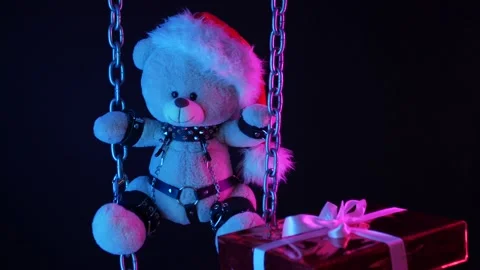 A teddy bear in a Santa Claus hat is a Christmas gift for BDSM games on chains Stock Footage 165225816