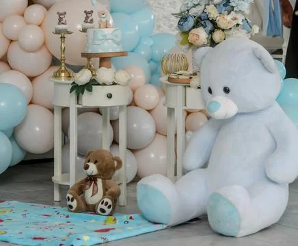 Teddy bear sits on background with different colors of balloons, birthday gar Photos