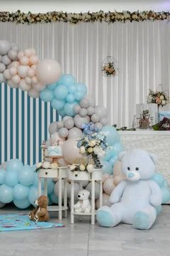 Teddy bear sits on background with different colors of balloons Photos