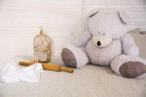 Teddy bear sitting on a bed next to a caged little bear Stock Photos