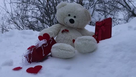 Teddy bear sitting in deep snow with red gift boxes and hearts. Winter outdoor s Stock Footage 327973426