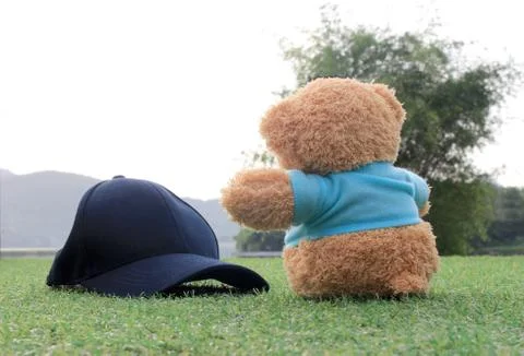 Teddy bear sitting on the grass with cap gap . Concept about travel Stock Photos