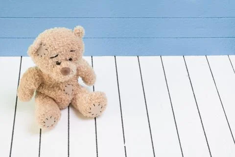Teddy bear sitting on white wooden floor with blue-green background lonely Stock Photos
