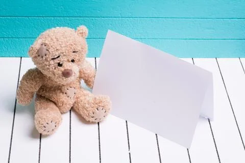 Teddy bear sitting on white wooden floor in blue-green background with blank Stock Photos