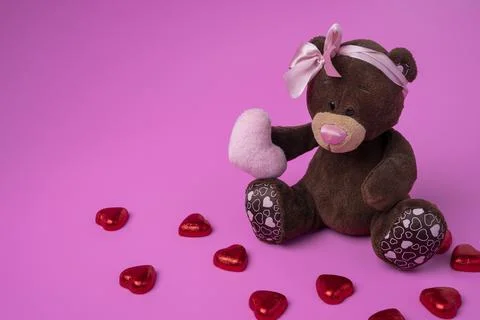 Teddy bear teddy bear holds a fluffy heart in his paws. Pink background Stock Photos