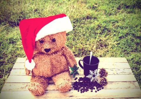 Teddy bear wearing santa claus hats and coffee cup on a wooden table Stock Photos