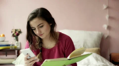 Teeange girl checking something on her phone and writing in the notebook Stock Footage 58321041