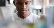Teen African American Boy Choosing Book In Library Stock Footage