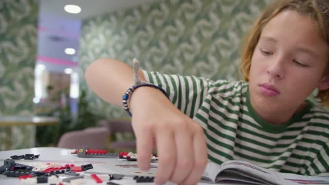 Teen assembling plastic block constructor at cafe Stock Footage 252735569