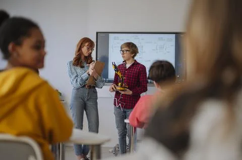 Teen boy explaining robotics project during science and technology class. Stock Photos