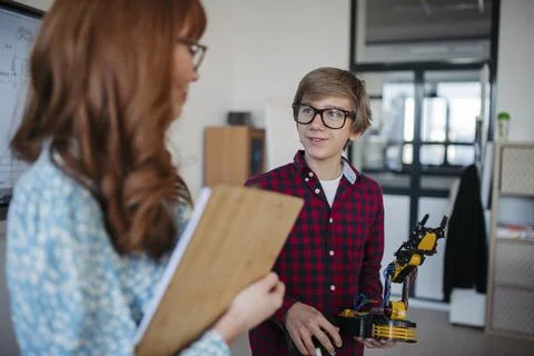 Teen boy explaining robotics project during science and technology class. Stock Photos