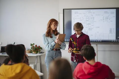 Teen boy explaining robotics project during science and technology class. Stock Photos